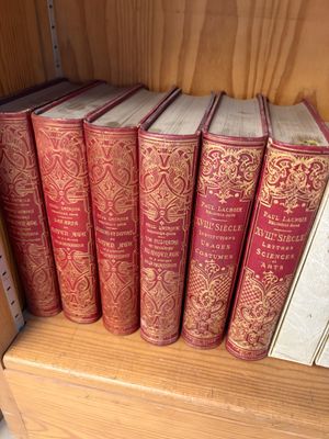 Plusieurs livres rouges sont alignés sur une étagère d'une bibliothèque