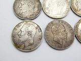 six silver coins of different sizes and shapes on a white surface