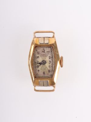 une montre en or posée sur une surface blanche