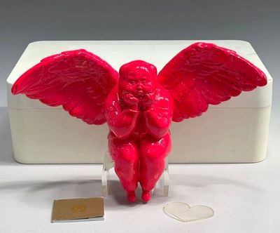 a red angel figurine sitting on a clear base