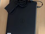 un ordinateur portable Dell avec son cordon d'alimentation et son chargeur, posé sur une table en bois