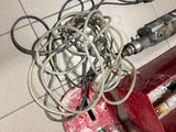 a red machine that is sitting on the floor next to a pile of wires