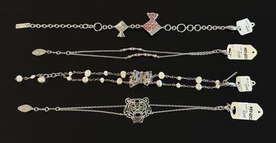 cinq bracelets différents avec des étiquettes et des breloques sur fond noir
