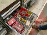 un homme qui se tient à côté d'un tiroir rempli d'outils