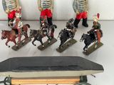 several figurines of soldiers riding on horses next to a wooden cart