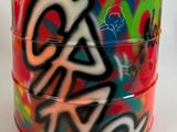 un récipient rouge orné de graffitis, posé sur une surface blanche