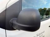 a side view mirror of a white van with a blue sky in the background