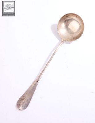une cuillère en argent avec un manche de cuillère sur une surface blanche