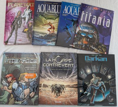 Plusieurs livres sont alignés sur un lit recouvert d'un drap blanc