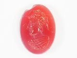 une image représentant un bouton en jade rouge orné du visage d'une femme