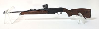 un fusil posé sur un support transparent, sur une surface blanche
