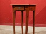 a small table with a drawer on it in front of a red wall