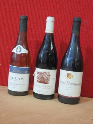 trois bouteilles de vin sont alignées sur une table en bois