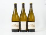 trois bouteilles de vin posées les unes à côté des autres sur une surface blanche