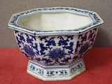 un pot de fleurs bleu et blanc posé sur une table rouge