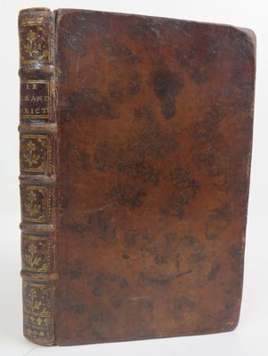 un vieux livre à la couverture brune posé sur une surface blanche