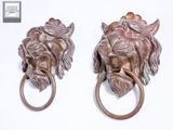 pair of bronze lion head door knockets on a white background