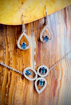 a close up of a necklace and earrings on a wooden surface