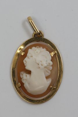 un gros plan sur un pendentif plaqué or orné d'un camée représentant une femme