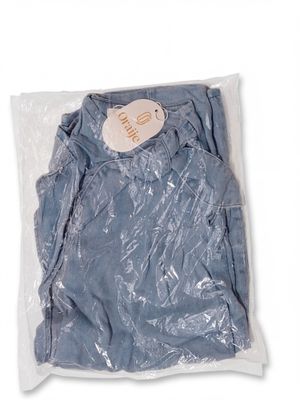 La chemise bleue est emballée dans du plastique et porte une étiquette