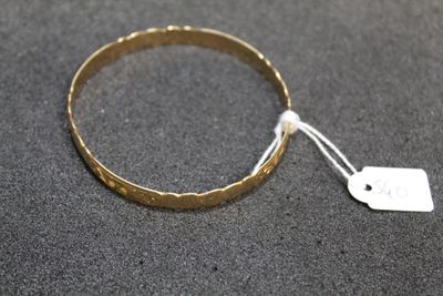 a close up of a gold bracelet with a tag on it