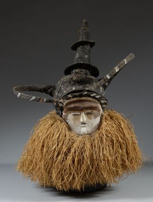 un gros plan sur un masque orné d'une longue barbe et d'un chapeau posé dessus
