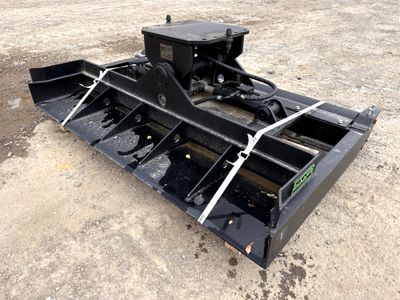 un gros plan d'un accessoire noir pour chargeuse compacte sur un terrain en terre battue
