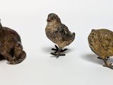 three small figurines of animals on a white surface