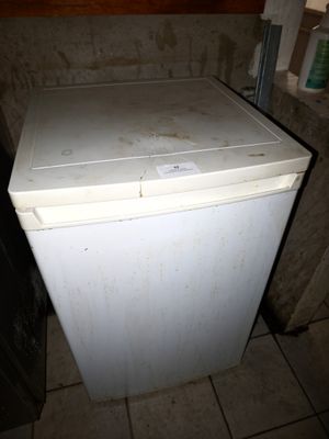 un petit réfrigérateur blanc dans le coin d'une pièce