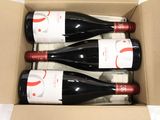 three bottles of red wine in a cardboard box on a table