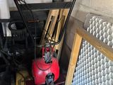 a red snow blower sitting in a garage next to a pile of tools