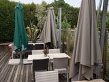 des tables et des chaises sur une terrasse équipée de parasols, par une journée nuageuse