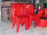 four red chairs sitting in front of a brick wall