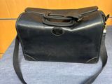 un vieux sac à main noir posé sur une table bleue