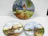 three decorative plates with windmills on them sitting on a table