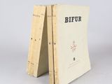 un vieux livre posé sur une table en bois à côté d'un mur blanc