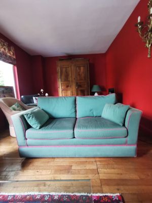 un canapé bleu dans un salon aux murs rouges