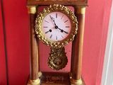 une horloge posée sur une table devant un mur rouge