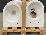 two white toilets sitting on a pallet in a room