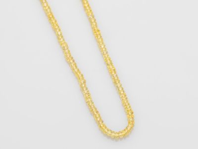 un collier en or dont la chaîne est posée sur un fond blanc