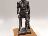 bronze statue of a man with a cane standing on a wooden base