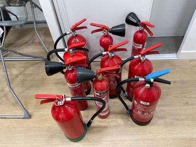 several fire extinguisors are lined up on the floor next to each other