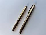 deux stylos sont posés l'un à côté de l'autre sur une surface blanche