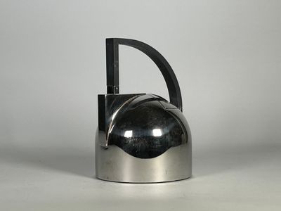 une théière en argent avec une poignée noire posée sur une table