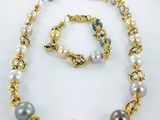 a close up of a necklace and bracelet on a white surface