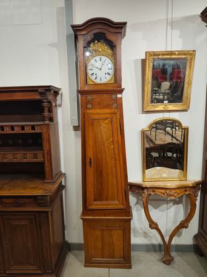 une horloge de parquet posée à côté d'une table sur laquelle se trouve un miroir