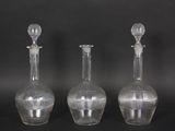 three clear glass vases sitting next to each other on a black surface