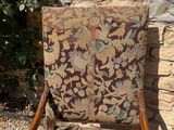 an old chair sitting in front of a stone wall next to a bush