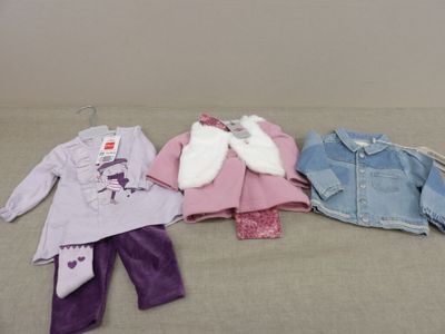 Des vêtements d'enfants sont alignés sur un lit