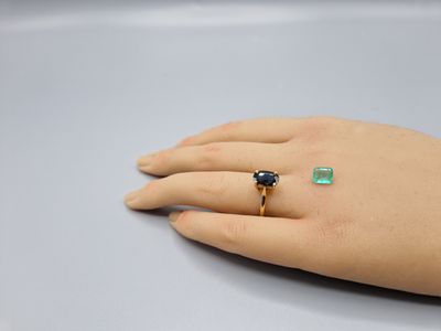 une image représentant la main d'une femme tenant une bague sertie d'une pierre verte